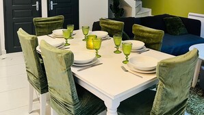 A dining area with a white table set for four, green upholstered chairs, and a decorative globe light fixture above. - 20 MIN PARIS/ 10 MIN ORLY AIRPORT CASA PARADIS VERT (Villeneuve-le-Roi)