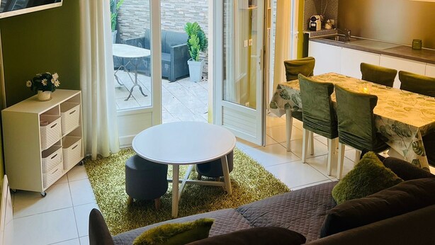 A modern living room with a sofa, a dining table, and a TV mounted on the wall. - 20 MIN PARIS/ 10 MIN ORLY AIRPORT CASA PARADIS VERT (Villeneuve-le-Roi)