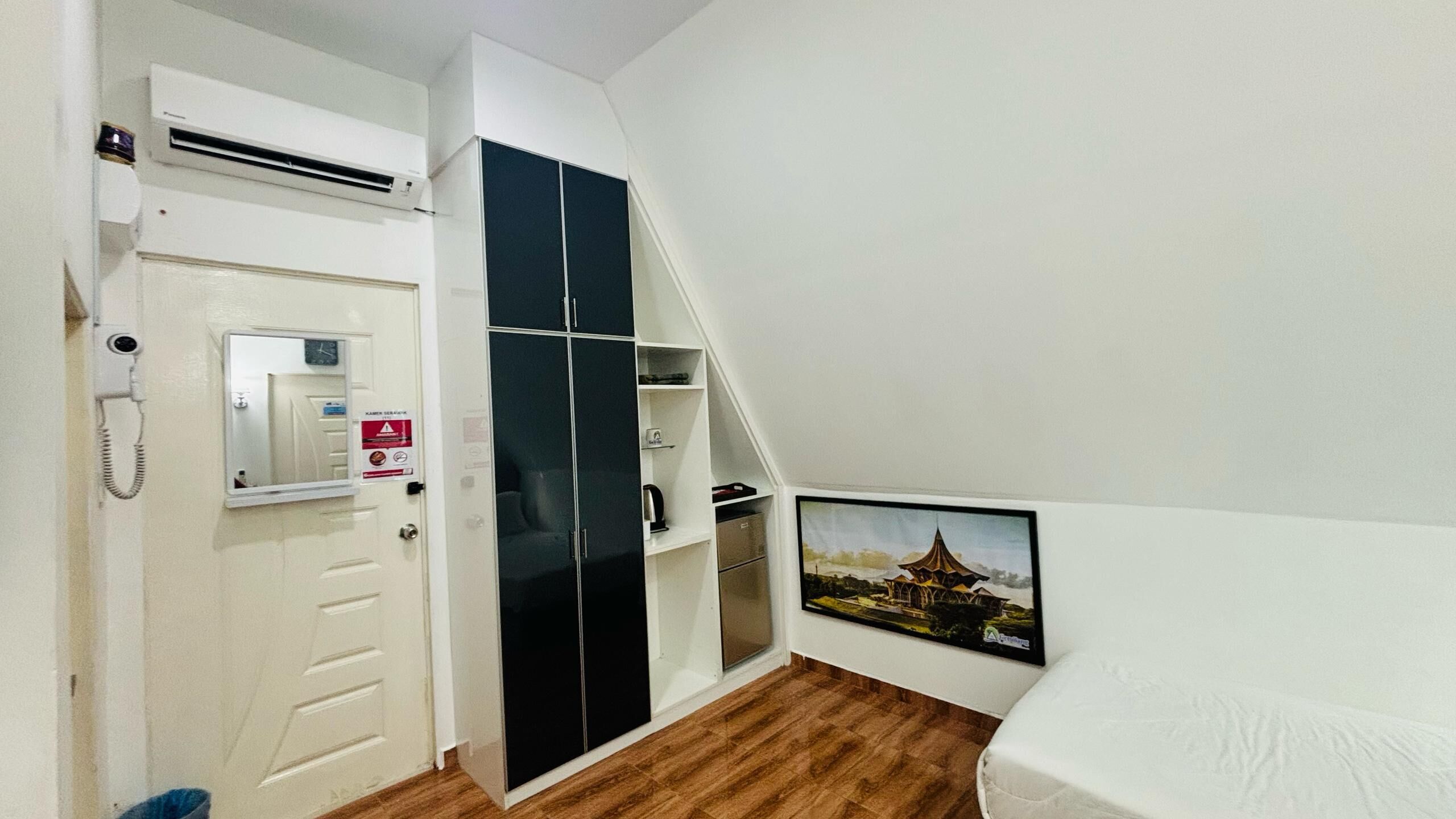 Una camera da letto con un letto, un armadio, uno specchio e un quadro appeso al muro.