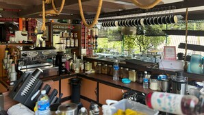 A bar area with a coffee machine, various bottles, and a counter with kitchen utensils. - Capital O 91167 Gemilang Candi Resort (Merbok)