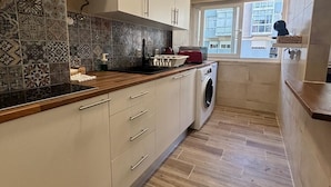 A modern kitchen with patterned tiles, wooden countertops, and a built-in washing machine.