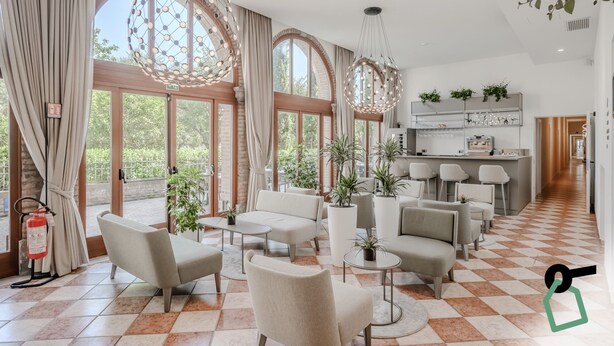A spacious living area with large windows, a kitchen with bar seating, and a fire extinguisher on the floor. - Hotiday Venezia Cape (Venice)