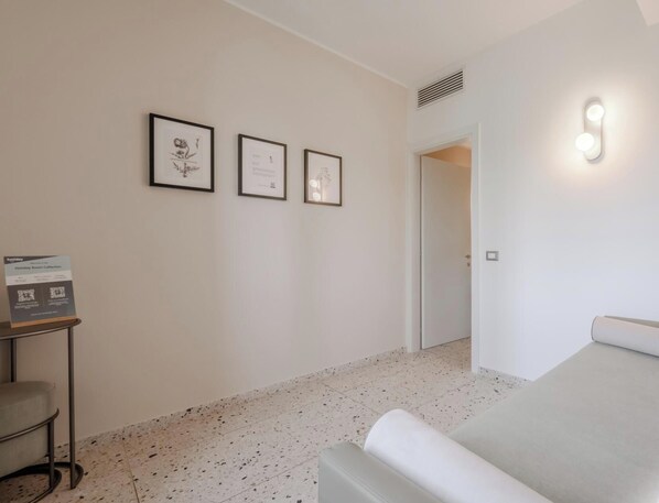 A hotel room with a bed, a small table with a sign, and three framed pictures on the wall. - Hotiday Venezia Cape (Venice)