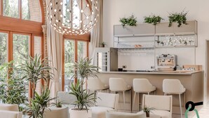 A modern interior with a bar area, seating, and potted plants. - Hotiday Venezia Cape (Venice)