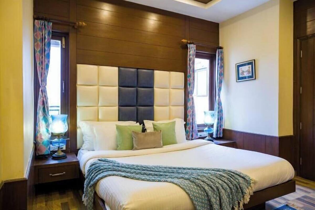 A bedroom with a large bed, wooden headboard, bedside tables, and curtains.