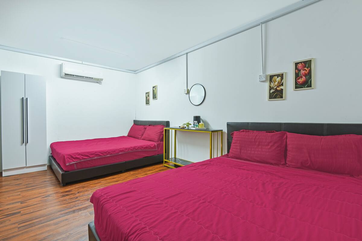 A room with two beds, a small table, and a mirror on the wall.