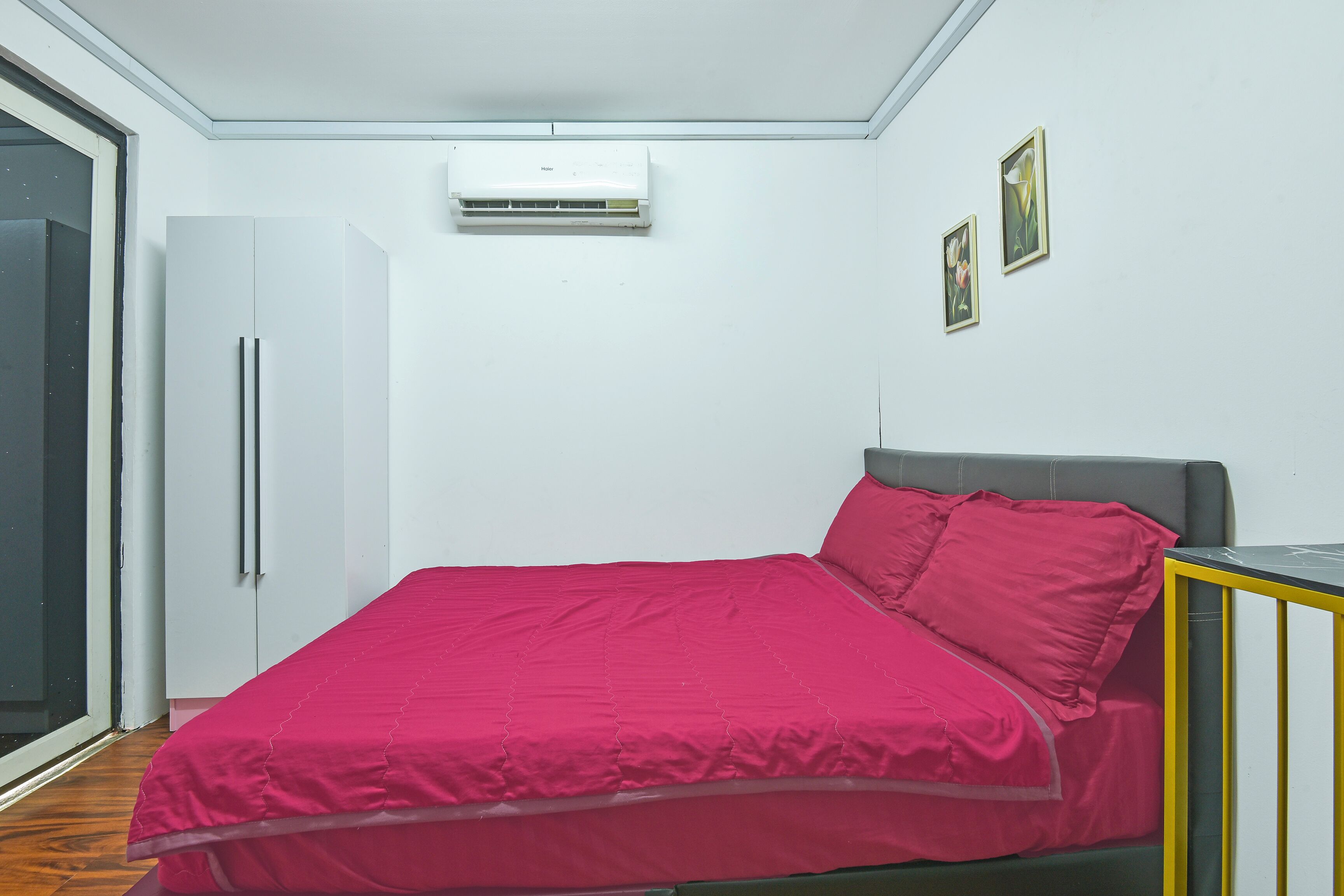 A bedroom with a bed, a wardrobe, an air conditioner, and a door.