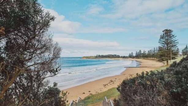 A coastal pathway leading to a beach with a clear view of the ocean and distant trees. - Beach Life on Price: 2  BR, 1  BA Townhouse in Torquay, Sleeps 8 (Torquay)