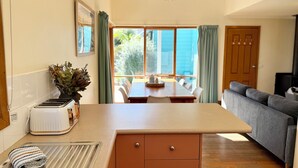 A kitchen with a wooden countertop, a sink, a toaster, and a dining area with a table and chairs. - Beach Life on Price: 2  BR, 1  BA Townhouse in Torquay, Sleeps 8 (Torquay)