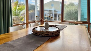 A dining area with a wooden table, a woven placemat, and a vase with dried flowers. - Beach Life on Price: 2  BR, 1  BA Townhouse in Torquay, Sleeps 8 (Torquay)