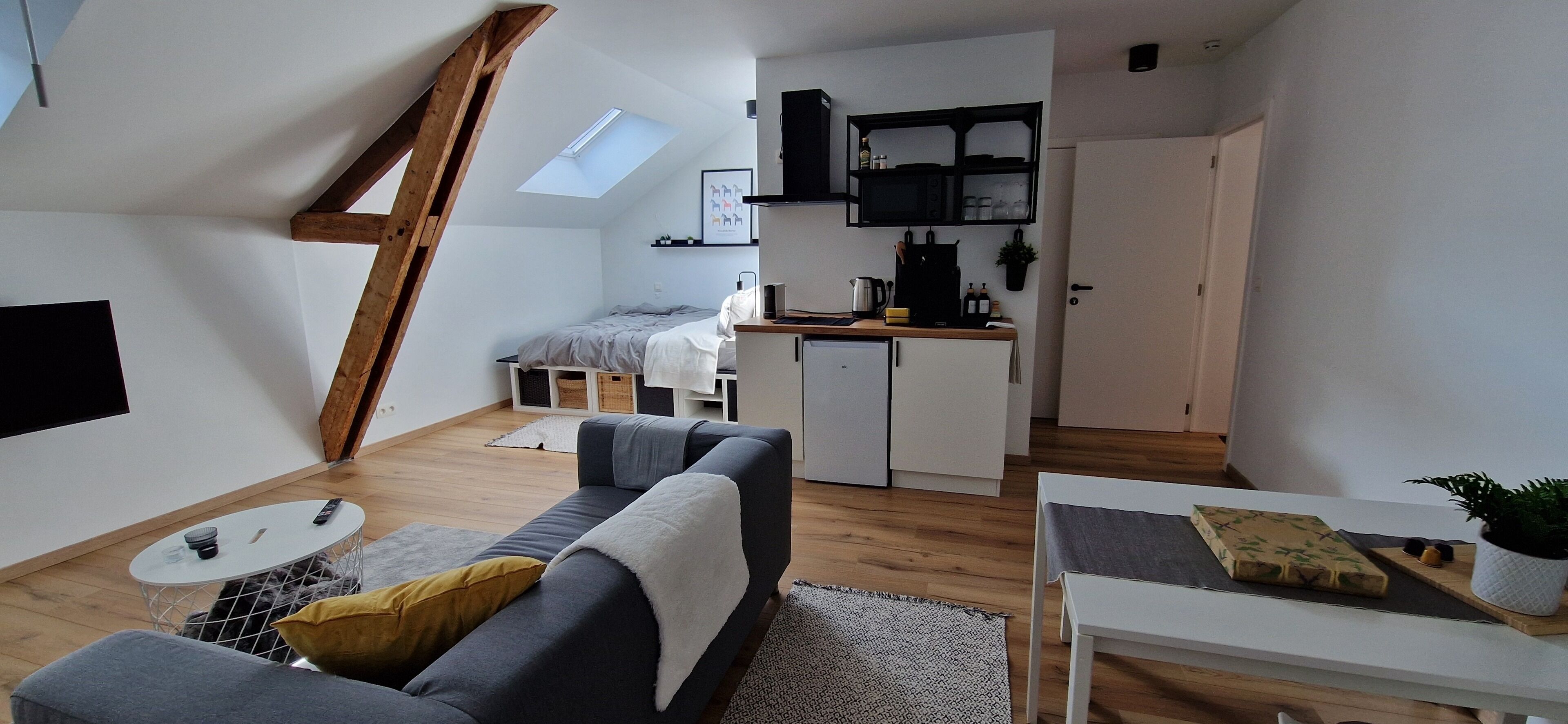 A compact living space with a loft bedroom, kitchenette, and a dining area.