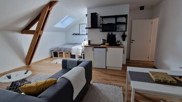 A compact living space with a loft bedroom, kitchenette, and a dining area.