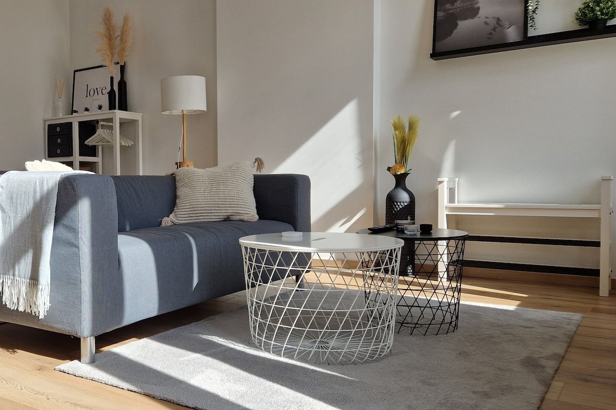 Een moderne woonkamer met een blauwe bank, een witte bijzettafel, een ronde salontafel en een wit kastje.