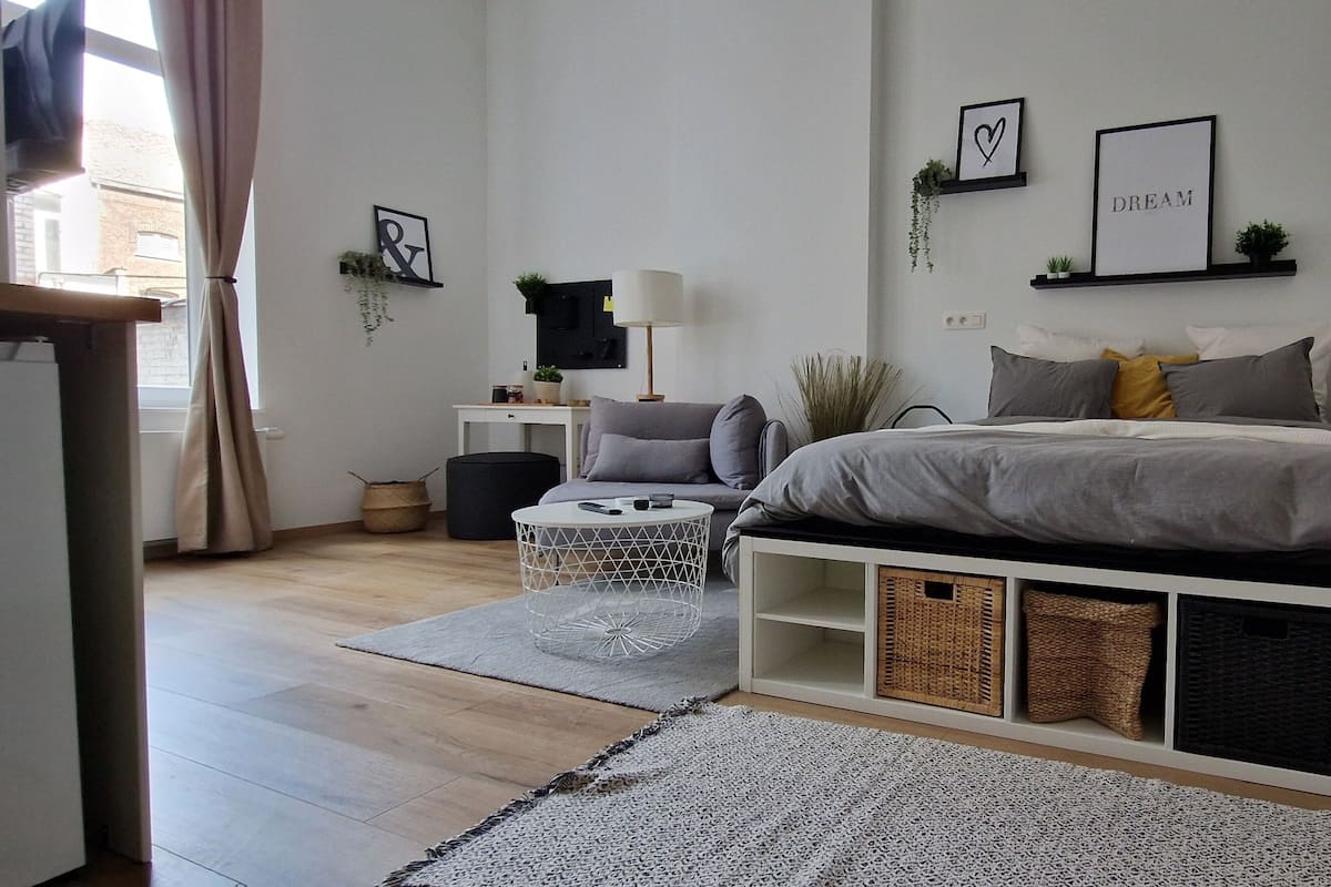Een moderne slaapkamer met een bed, nachtkastjes, een bureau en een kledingkast.