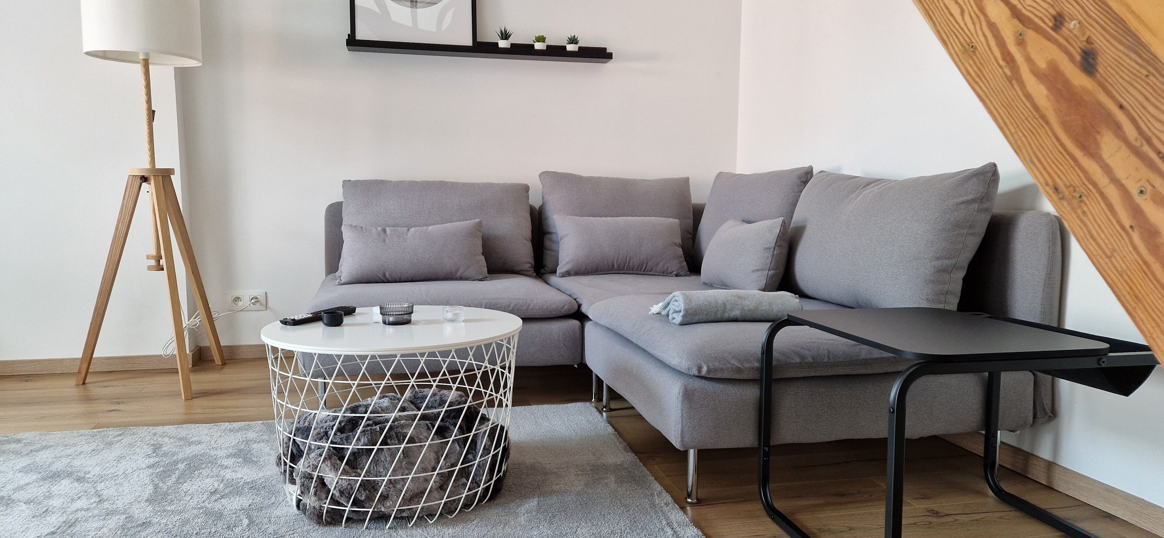 Una sala moderna con un sofá seccional gris, una mesa redonda de centro y una mesita auxiliar.