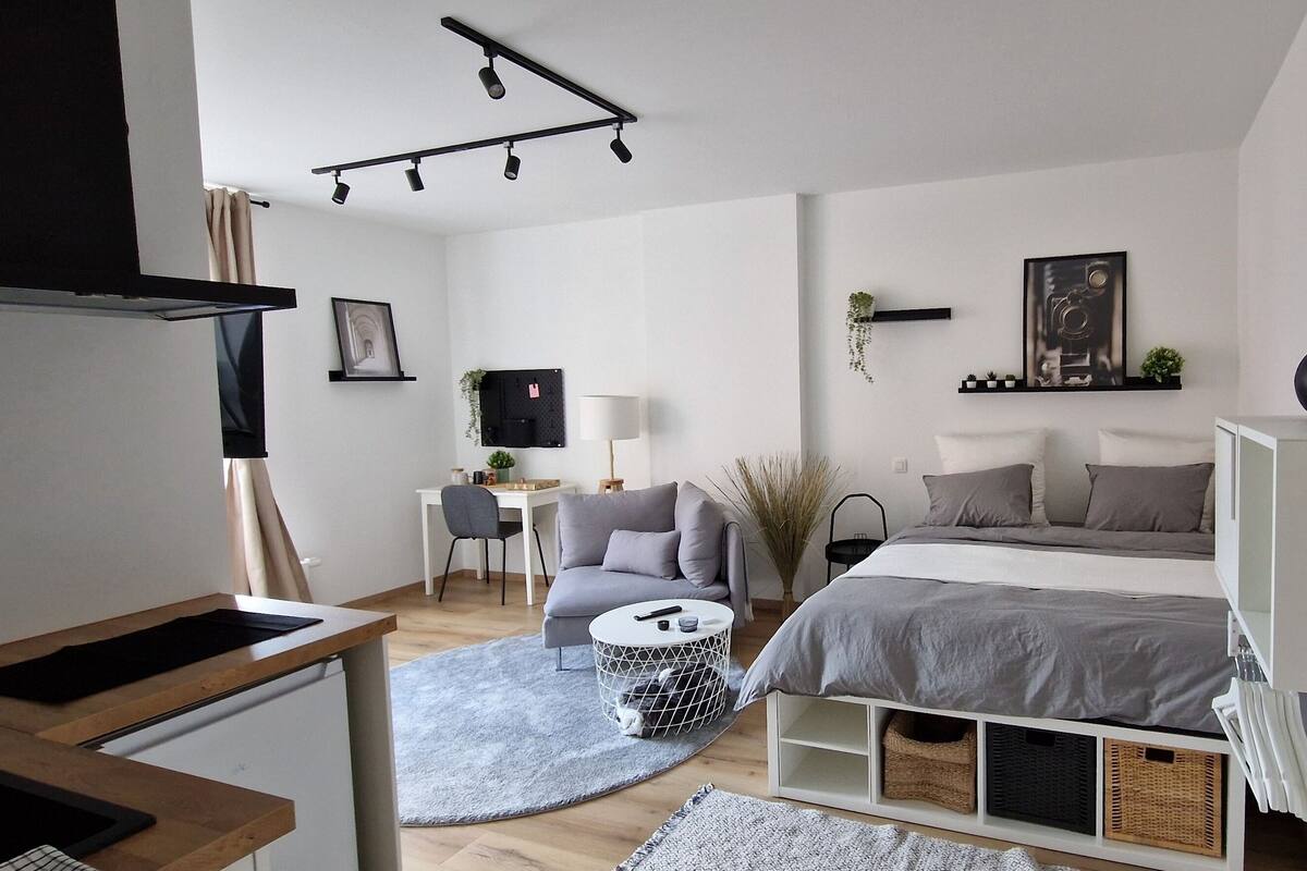Een moderne slaapkamer met een bed, nachtkastjes, een bureau en een stoel.
