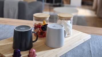 Una mesa de madera con una bandeja que contiene dos tazas, un tarro de caramelos y un pequeño recipiente.