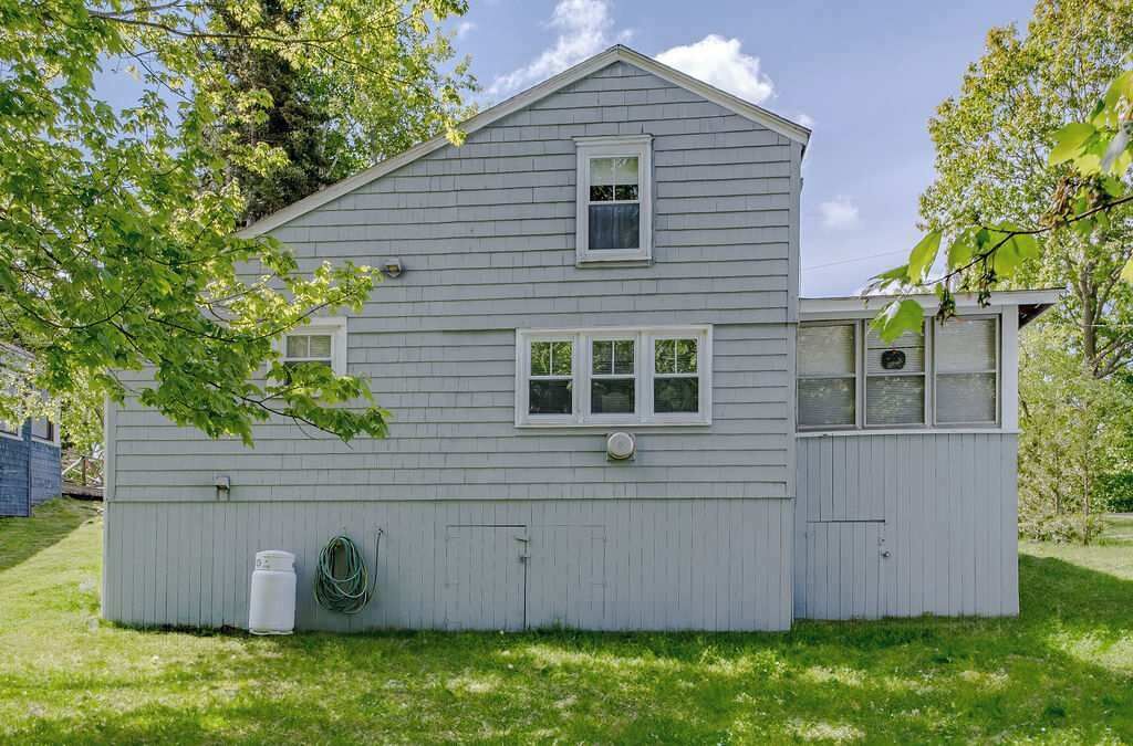 Ein zweistöckiges Haus mit Satteldach, einer Veranda und einer Garage.