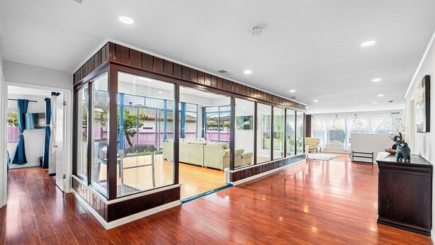 A spacious room with wooden flooring, large windows, and a view of the outdoors.
