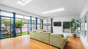 A spacious living room with a large sectional sofa, a dining area, and a view of the backyard through large windows.