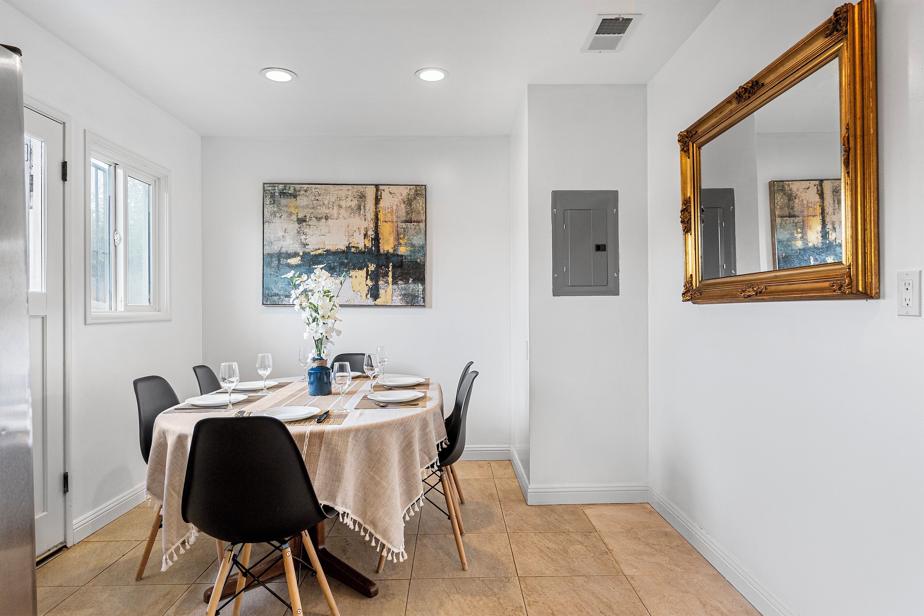 A dining area with a round table, chairs, and a large mirror on the wall.