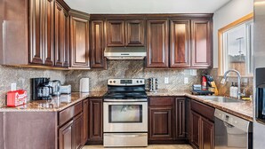 A kitchen with dark wood cabinets, stainless steel appliances, granite countertops, and a built-in oven.