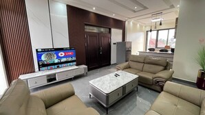 A modern living room with a flat-screen TV, leather sofas, a marble coffee table, and a built-in entertainment unit. - GARDEN PARK HOUSE (Kigali)
