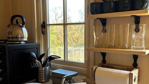 A kitchen with a kettle, utensils, and a bouquet of yellow roses on the counter.