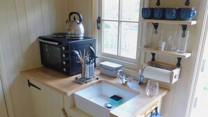 A compact kitchen with a sink, kettle, and storage shelves.
