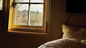 A bedroom with a window, a bed, and a wall-mounted TV.