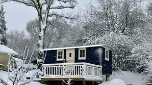 A snow-covered house with a balcony and a porch.