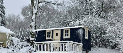 A snow-covered house with a balcony and a porch.