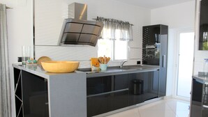 A modern kitchen with a large island, stainless steel appliances, and a black and white color scheme. - Luxury villa with stunning sea views, walking distance from El Portet beach. (Teulada)