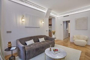 Una sala de estar moderna con un sofá gris, una mesa de centro redonda y un sillón beige.
