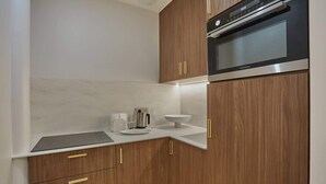 Een kleine keuken met houten kastjes, een ingebouwde oven en een wit aanrecht.