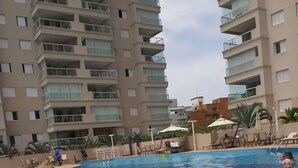 Ein Schwimmbeckenbereich mit Fliesenböden, Liegestühlen und Sonnenschirmen.