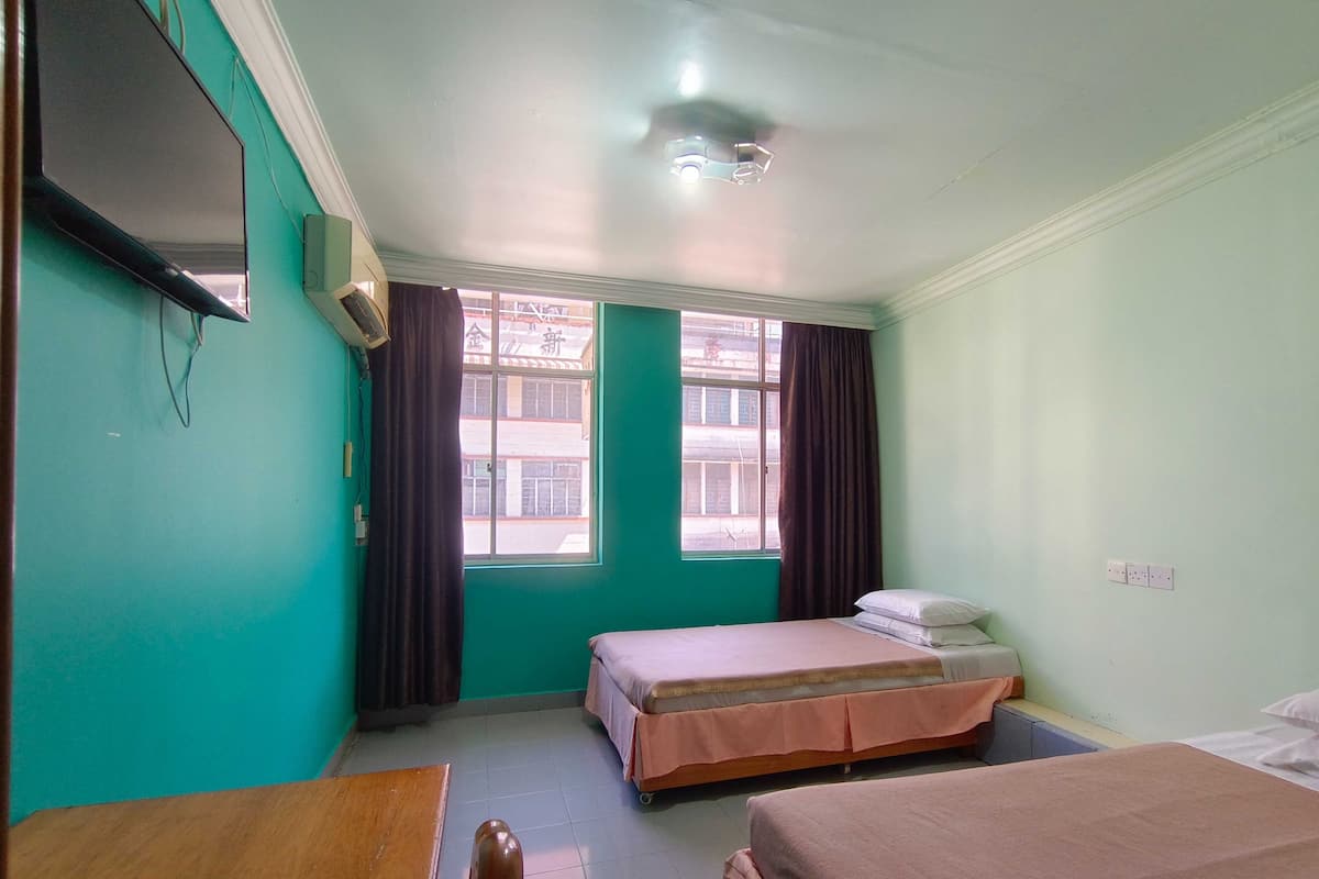A room with two beds, a TV, and a window with curtains.