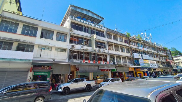 A multi-story building with a sign reading "Malaysia Hotel" and several ground-level shops. - Hotel O Malaysia Hotel (Sandakan)