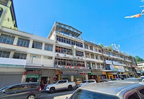 En byggnad med flera våningar, med en skylt som visar texten ”Malaysia Hotel”, och ett antal butiker på gatunivå.