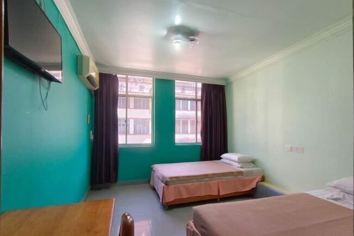 A room with two beds, a TV, and a window with curtains.