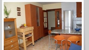A compact kitchen with a central island, wooden cabinets, and a refrigerator. - Apartment with 2 double bedrooms (4 persons), 1 bathroom at 400 meters from the beach (Boiro)
