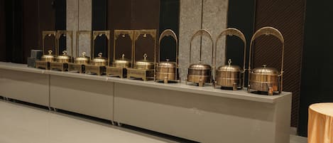 A row of gold-toned, ornate containers on a sleek, modern counter in a hotel lobby.