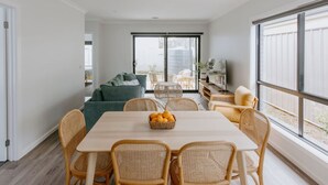 A modern living room with a dining area, large windows, and a view of the outdoors. - Close to town & hospital, quiet & private location (Sale)