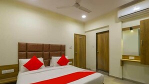 Habitación de hotel con cama, ventilador de techo, aire acondicionado y armario de madera.