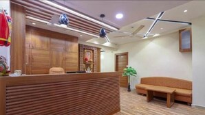 Zona de recepción con mostrador de madera, un sofá y una planta en maceta.