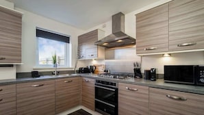 Une cuisine moderne avec des meubles en bois, une hotte en acier inoxydable, un four à micro-ondes et un four encastré.