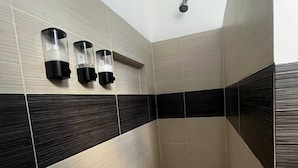 Une douche moderne dotée d’un plafond incliné et d’un pommeau de douche à pluie.