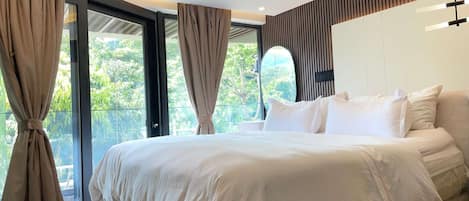 Un dormitorio moderno con una cama grande, cortinas y vistas al verdor.