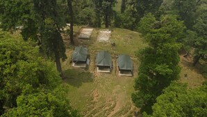 An aerial view of a campsite with four tents arranged in a semi-circle, surrounded by dense forest. - The Little Pahadi (Ukhimath)
