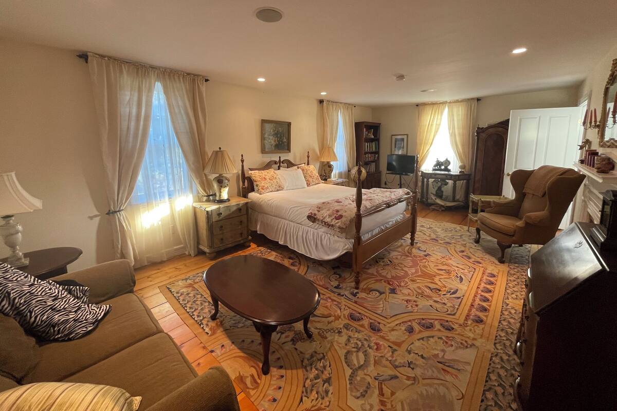 Une chambre bien éclairée, avec un grand lit, un canapé, une table basse et un téléviseur.